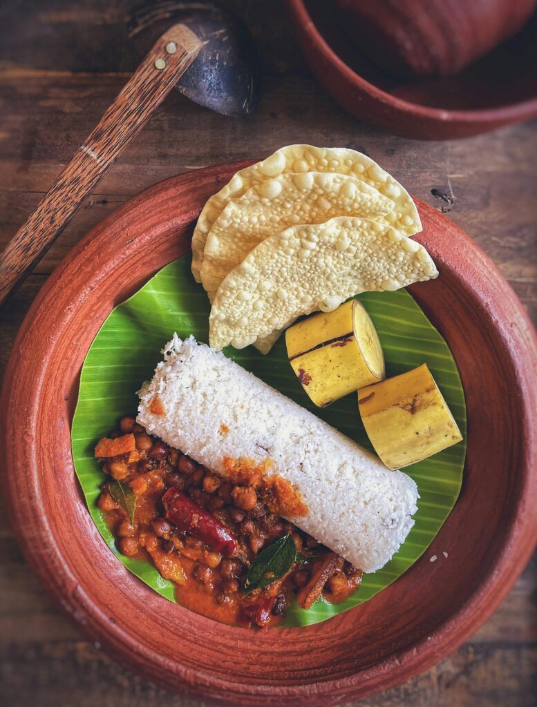 A delicious south indian breakfast featuring puttu, curry, banana, and poppadoms.